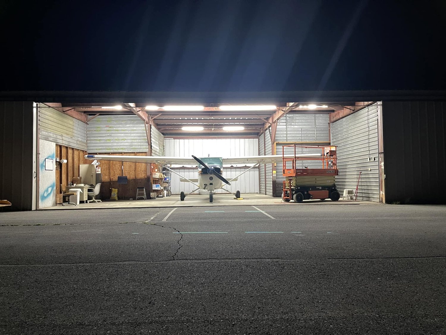 The club airplane inside the illuminated hangar at night