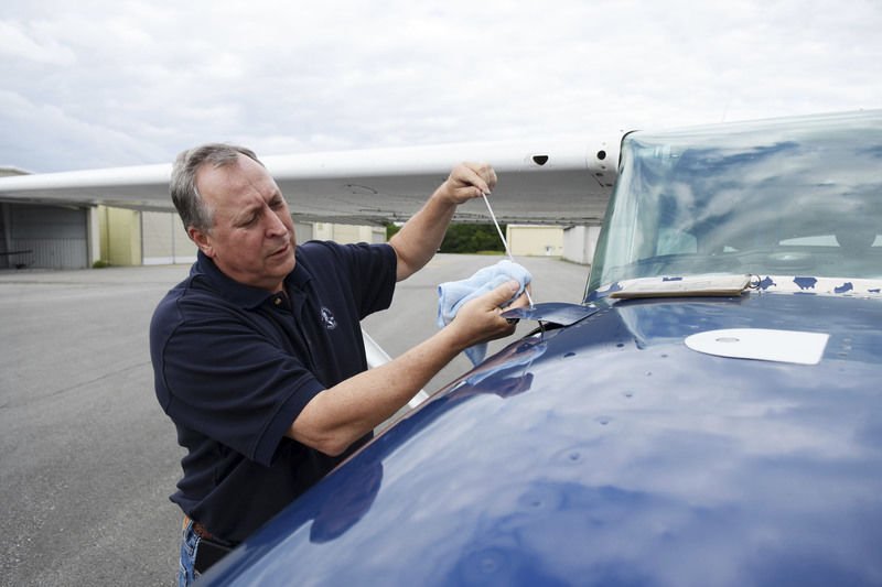 A member checking the airplane’s oil dipstick